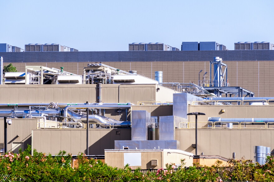 Exterior of a data center with rooftop equipment, exposed pipes and large metal ducts in Silicon Valley, South San Francisco Bay Area, California.