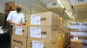 Superintendent Dr. Henderson Lewis Jr. stands next to boxes of personal protective equipment.