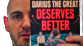 Adib Khorram displays a copy of his YA title "Darius the Great Deserves Better."
