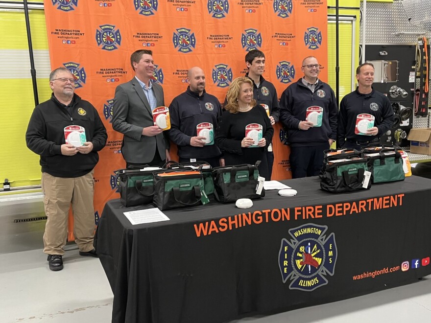 Illinois Fire Safety Alliance's Margaret Vaughn (middle), Washington Firefighters and other state and regional fire officials show off sealed ten-year battery model smoke detectors.