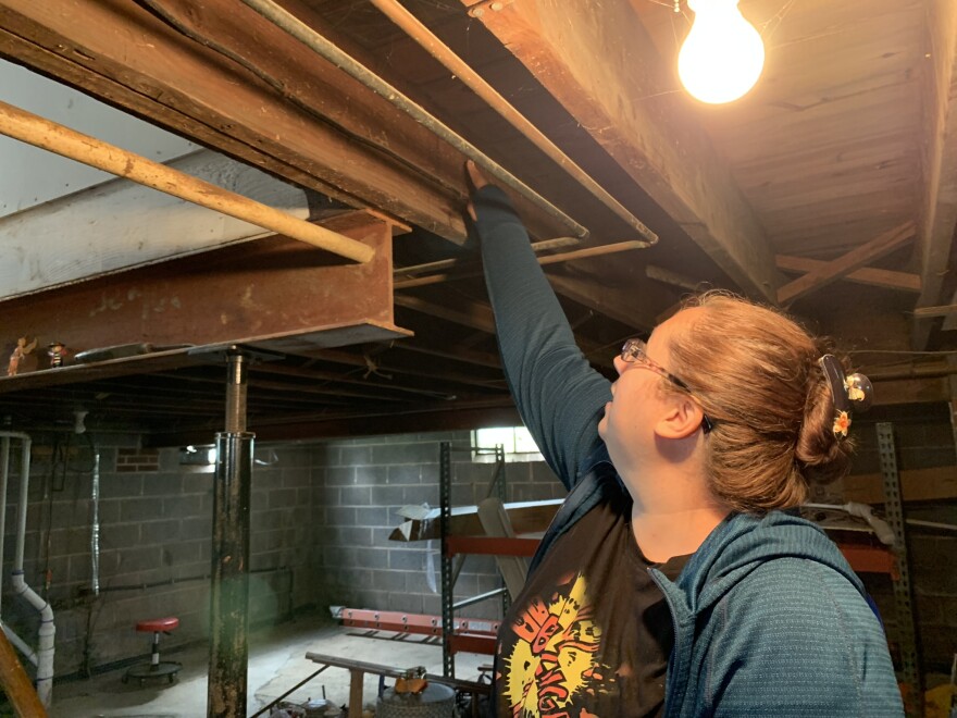 Samantha Sharp points to debris left by floodwater on the beams of her basement ceiling on Aug. 10, 2022.