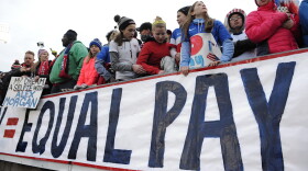 Fans stand behind a large sign for equal pay for the women's soccer team during an international friendly soccer match in 2016. (Jessica Hill/AP)