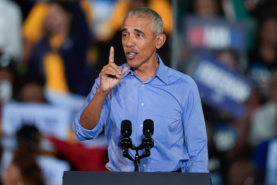 Former President Barack Obama speaks into a microphone on a podium at a rally