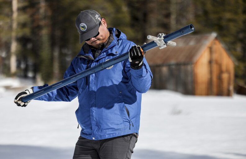 In this photo provided by the California Department of Water Resources, manager Sean de Guzman, right, examines the aluminum snow depth survey pole during the second survey of the season at Phillips Station, Calif., Tuesday, Jan. 30, 2024. The water content of California's mountain snowpack is just over half of normal. The California Department of Water Resources says electronic measurements statewide on Tuesday show a snow water equivalent of 8.4 inches or 52% of average to date. (Xavier Mascareñas/California Department of Water Resources via AP)