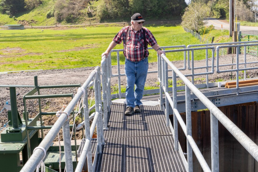 Fred Messerly walks on a metal grate walkway over a tide gate.