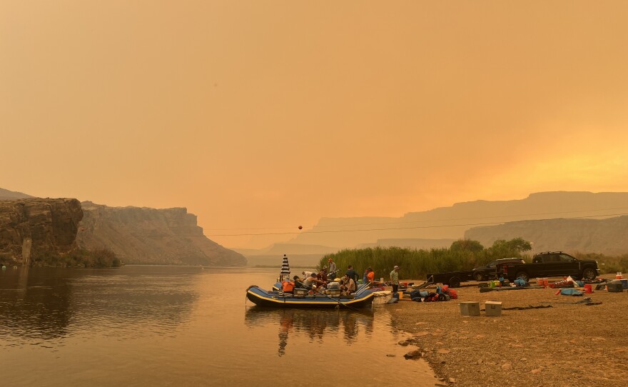 Rafters rig their boats under the orange glow of wildfire smoke Saturday. Within Grand Canyon National Park, all corridor trails remain closed except for those joining or leaving river trips. Boat Beach has reopened for river runners to stop and refill water; however, they must continue to Pipe Creek beach for passenger exchanges.