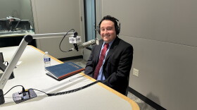 A man sits in front of a microphone for an interview with headphones on