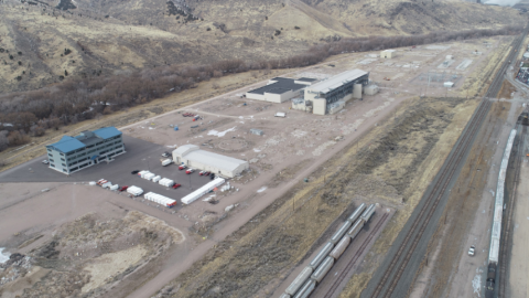 Aerial view of a partly-developed area near a railroad. It has a few large buildings scattered across but is otherwise empty.