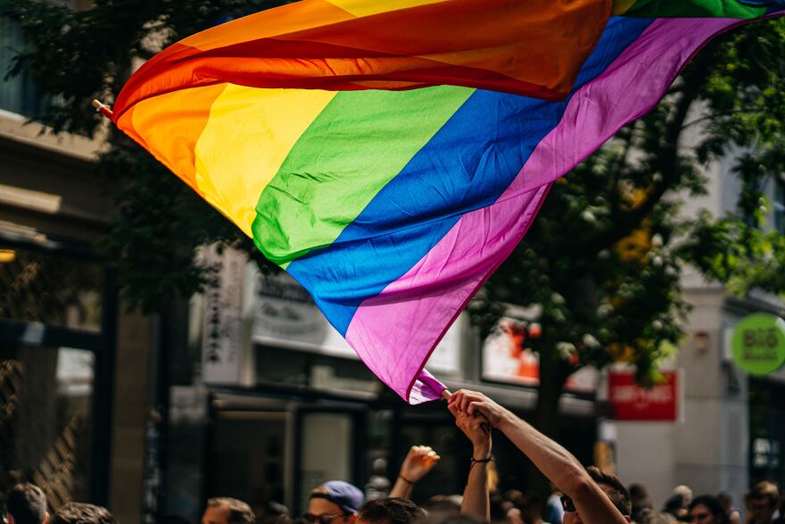 Person waving LGBTQ pride rainbow flag in crowd