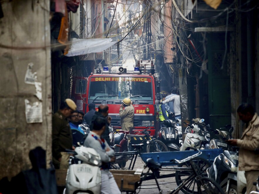 A fire engine stands by the site of the fire in an alleyway, tangled in electrical wire and too narrow for vehicles to access.