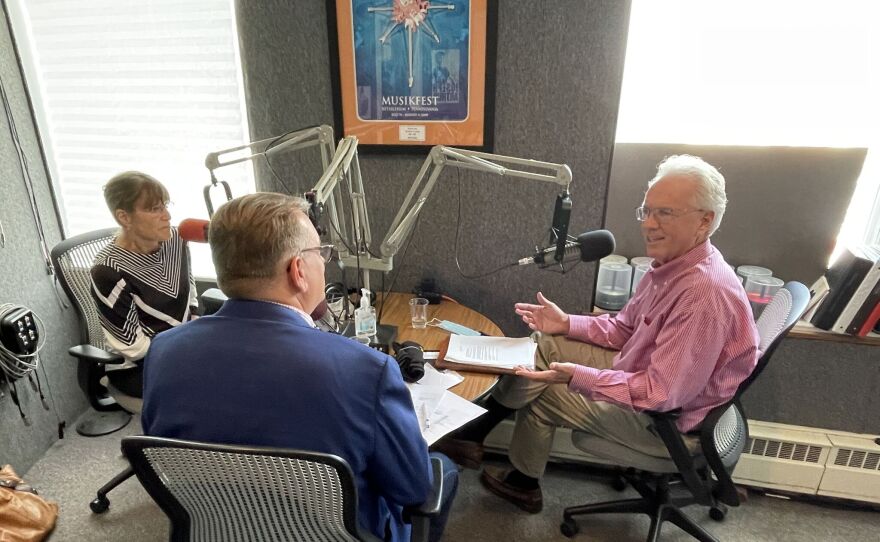 Tom Garrity, Scott Burky, and Sally Handlon seated around a table behind microphones in the WDIY studios.