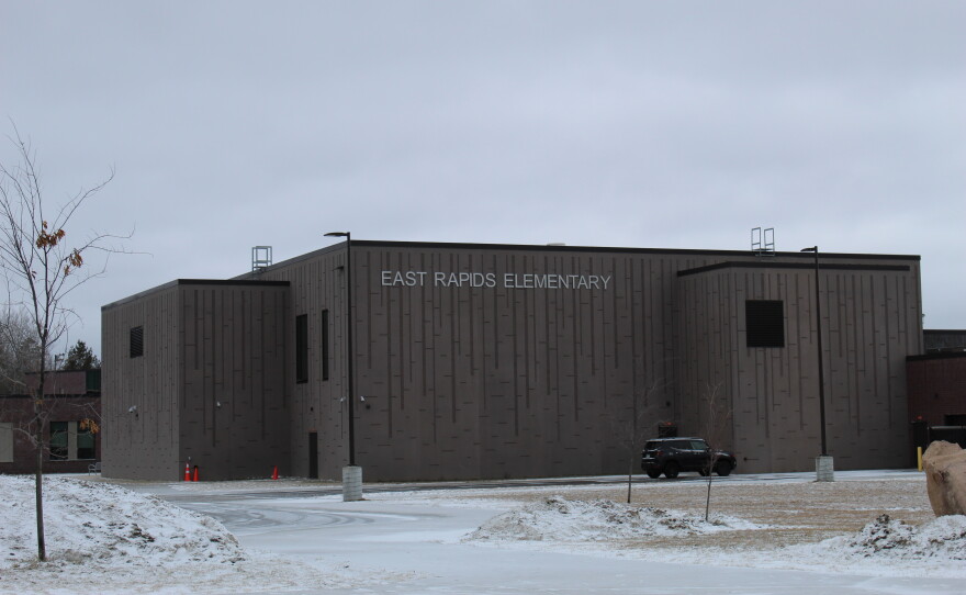 A large gray building on a snowy day. The side of the building says East Rapids Elementary in capital white letters.