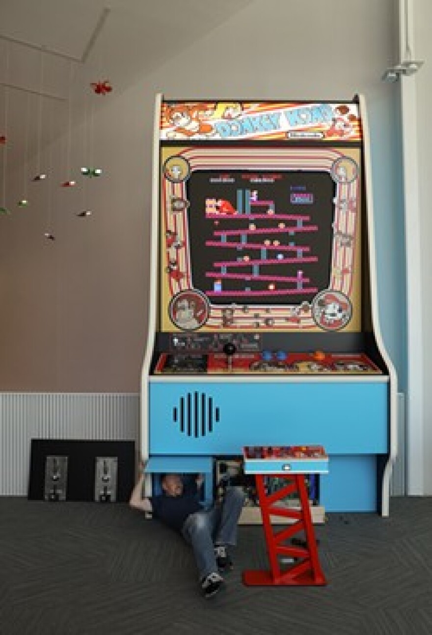 Martin Reinhardt, Arcade Game Conservation Technician at The Strong, climbs out of the 20-foot tall Donkey Kong arcade game.