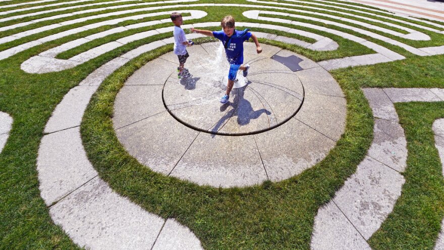 Dylan Schoenfeld, 9, of California, leaps over a fountain while cooling off with his brother Charlie, 5, while on vacation during a summer heat wave, Thursday, July 21, 2022, in Boston. Dangerously high temperatures Thursday threatened much of the Northeast and Deep South as millions of Americans sought comfort from air-conditioners, fire hydrants, fountains and cooling centers. (AP Photo/Charles Krupa)