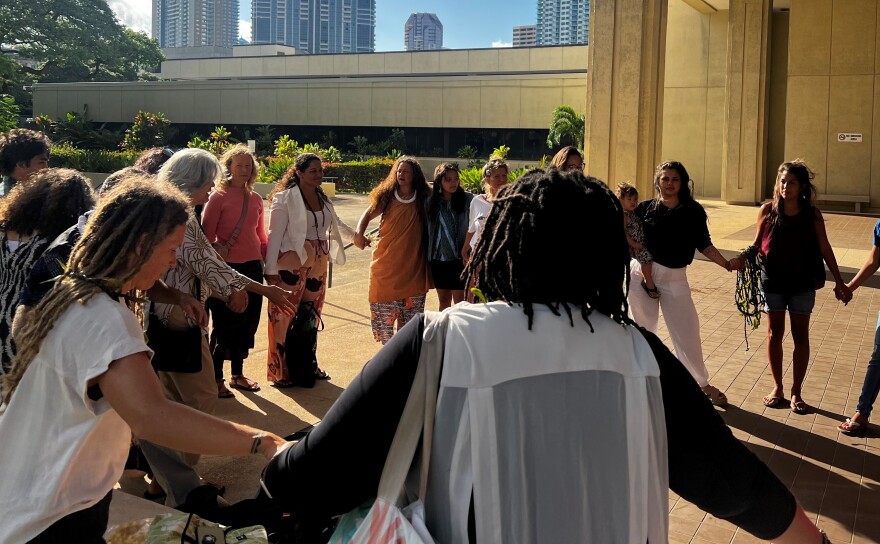 The plaintiffs — six midwives and three mothers — form a circle with their supporters to chant a pule, or prayer, before heading into court. (June 10, 2024)