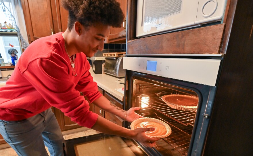 Aidan McFarlane places two sweet potato pies into the oven.