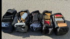 Several duffel bags of cocaine laid out on the road.