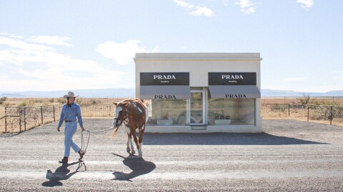 A model leads a horse around Prada Marfa during a photo shoot.