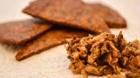 Chips made out of spent grain, next to a pile of spent grain. 