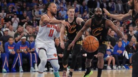 New York Knicks' Jalen Brunson, left, passes under the basket during the second half of Game 1 in the Eastern Conference finals NBA basketball playoffs series against the Cleveland Cavaliers, Tuesday, May 19, 2026, in New York. 