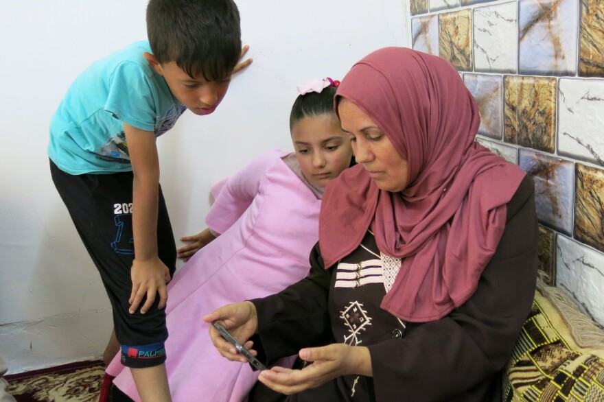 Fawzia Ahmed, along with her daughter and grandson, watches for the first time an Iraqi television interview with her wounded and captured son Khaled, on the day he was killed by a U.S. Navy SEAL.