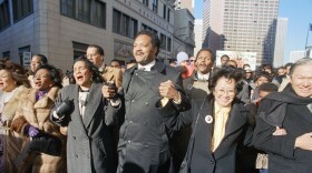 FILE - Coretta Scott King holds hands while singing with the Rev. Jesse Jackson and Christine Farris, the sister of Dr. Martin Luther King, Jr., as they parade on Peachtree Street in Atlanta on Monday, Jan. 19, 1987 to honor King's birthday. At left in Mrs. Alveda king Beall and at right is Lupita Aquino Kashiwahara. (AP Photo/Charles Kelly, File)