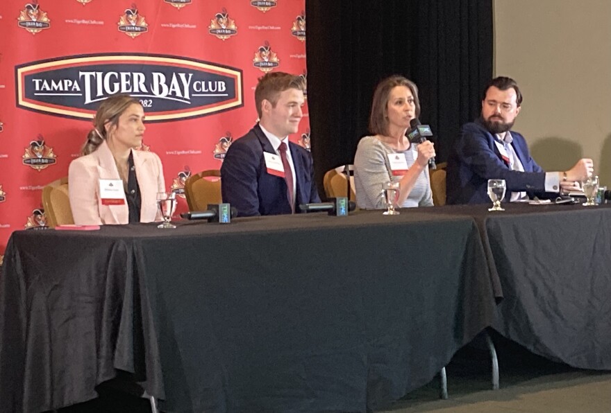 Two men and two women sitting side-by-side at tables with black tablecloths and Tampa Tiger Bay Club wall behind them