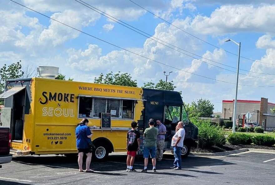 Exterior view of Smoke 'n' Seoul food truck with people waiting outside the truck.