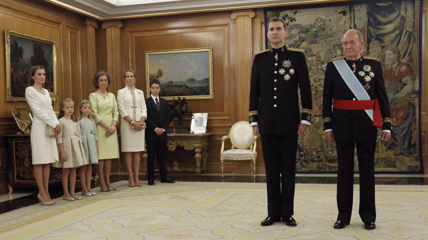 King Felipe stands next to his father, the former King Juan Carlos, while members of the royal family look on.