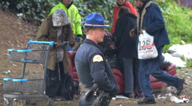 A Washington State Patrol trooper looks on as a homeless camp is cleaned out at the corner of Airport Way South and South Royal Brougham Way on Wednesday, January 27, 2016. That's a short way from where two people were shot to death in 'The Jungle.'