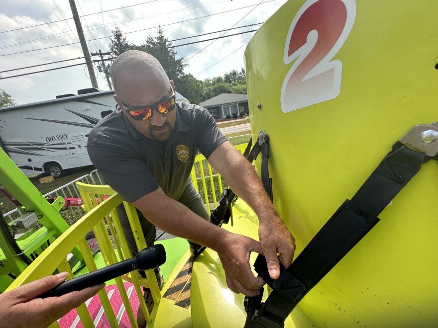 Chief Ride Inspector Ron Dean checks the safety harness on a portable carnival ride