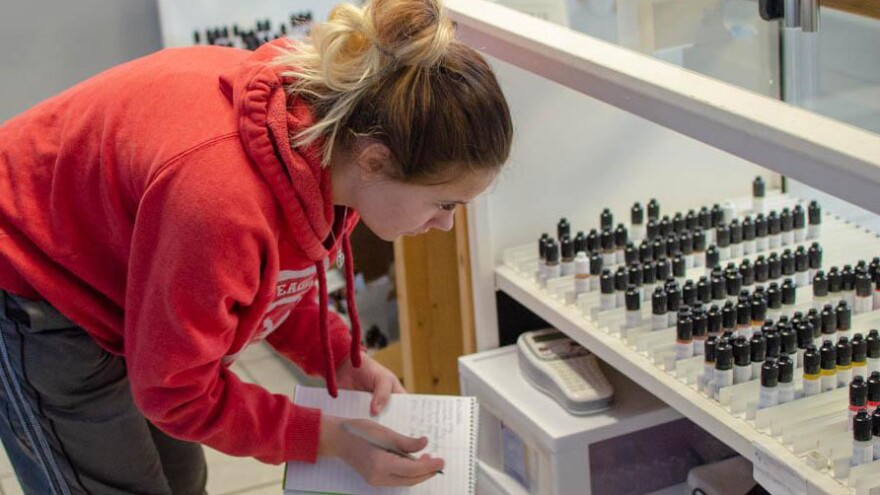 Faith White, an employee of Great Alternatives Vape Shop in suburban Des Moines, takes inventory of the store's vaping flavors.