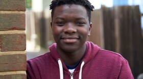 Portrait Of Smiling Teenage Boy Leaning Against Wall In Urban Setting