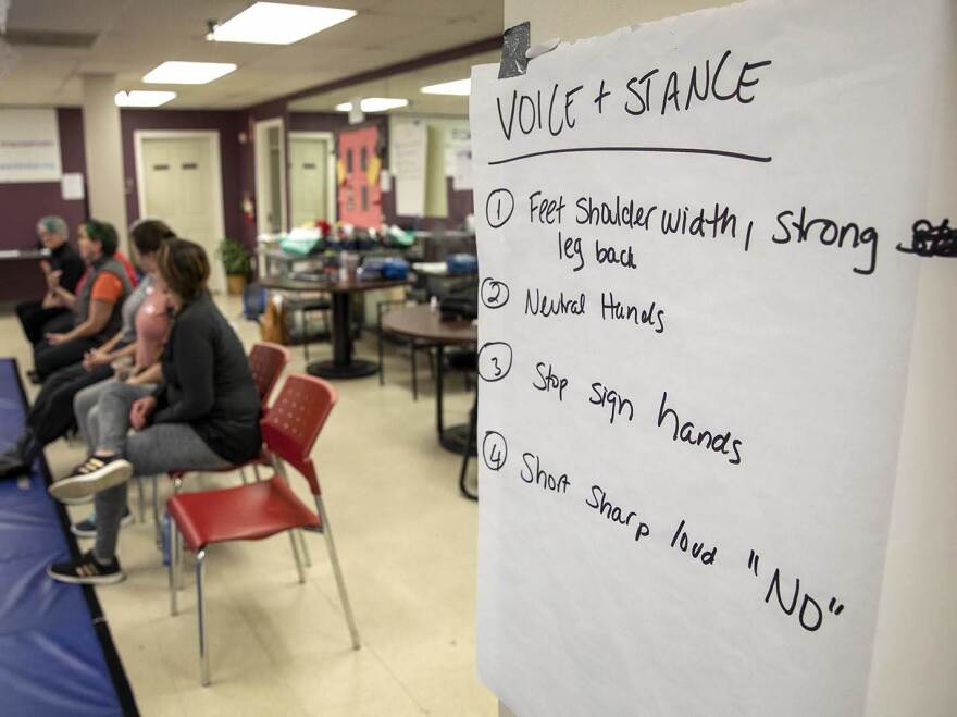 Self-defense notes hang on the walls around the mat at the IMPACT session.