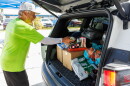 A volunteer with All Faiths Food Bank loads food into a car during a distribution event.
