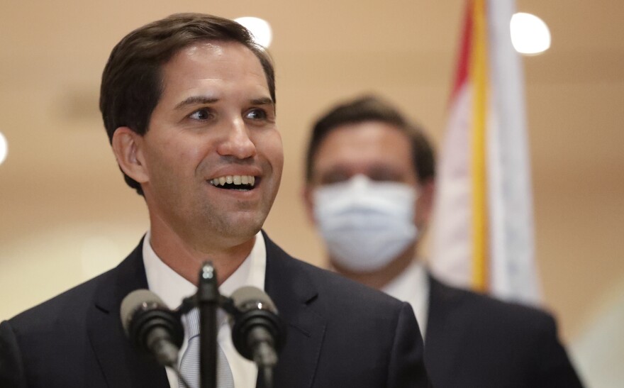 John Couriel smiles as he speaks during a news conference, Tuesday, May 26, 2020, at the Miami-Dade Public Library in Miami. Gov. Ron DeSantis, rear, appointed two South Floridians to the state Supreme Court on Tuesday: a Palm Beach County circuit judge who immigrated from Jamaica and Couriel, a former assistant U.S. attorney who is the son of Cuban immigrants. (AP Photo/Wilfredo Lee)