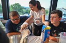 Aiden Thomas and Alex Clark work with University student Christina preparing the pancake batter.