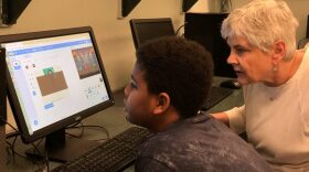 Matthew Washington, 10, calls on Edith Williams for help and watches as she shows him how to use the block-based code on Scratch. (Angel Ransby/WUFT News)