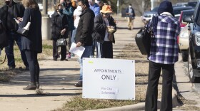 People waiting to get a vaccine at the Delco Activity Center wait in a line that wraps around the side of the building, in front of a sign that says "appointments only".