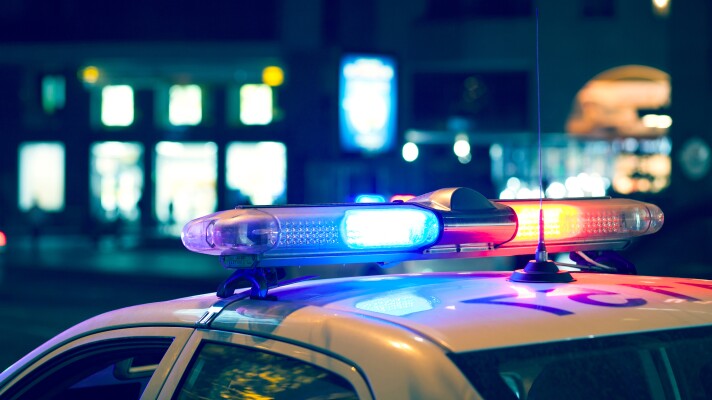 Blue light flasher atop of a police car. City lights on the background.