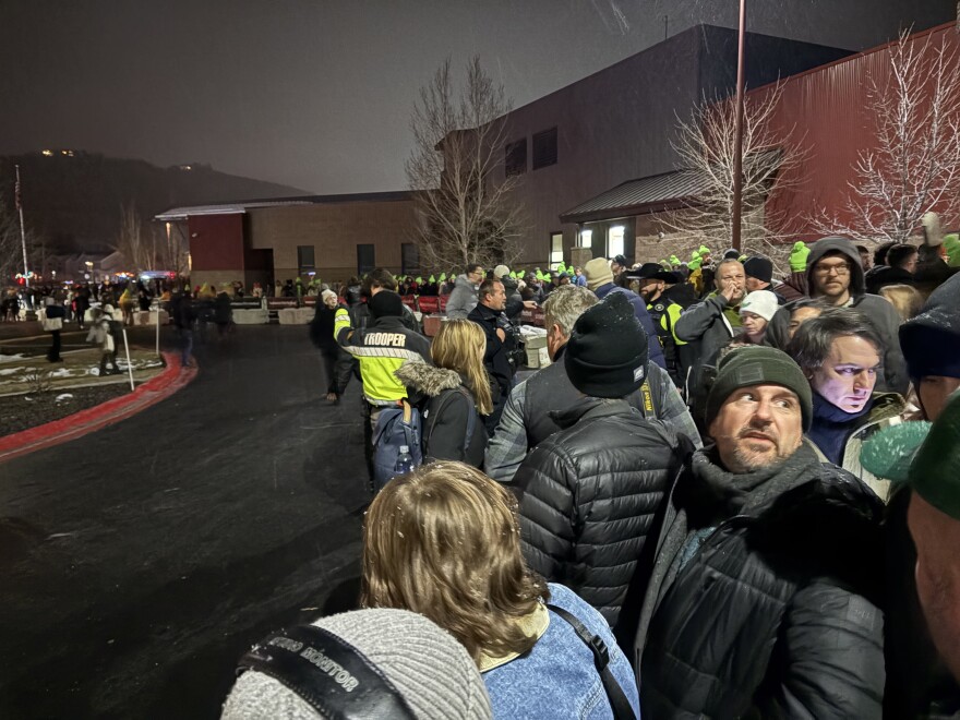 People in coats and hats stand outside on a cold, dark night in Park City, Utah.