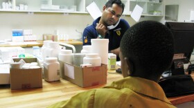 A boy waits to get his anti-AIDS drugs from pharmacist Rajesh Chandra at the Botswana-Baylor Children's Clinical Center of Excellence in Gaborone.