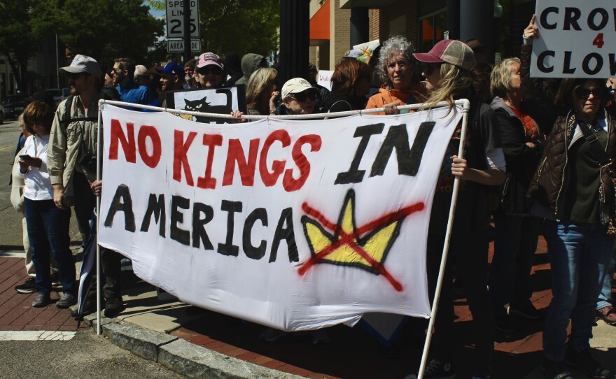 A group of protestors on the corner of 3rd and Princess street holding a large banner with "No Kings in America" painted on the front.