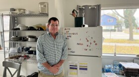 Sean Baxendale, program director and recovery coach at the Maple Leaf Flats, stands in the sober living facility kitchen, in front of a fridge that reads "Acts of Kindness are Free." (Photo: Claire Keenan-Kurgan/IPR)