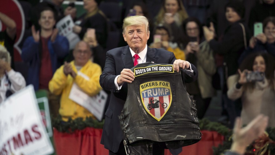 President Trump holds a vest reading "Bikers For Trump" during a rally Friday in Pensacola, Fla. There, he gave his most full-throated endorsement of Roy Moore for Senate in Alabama yet.