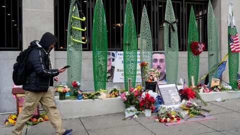 A person walks past a makeshift memorial for U.S. Army Spc. Sarah Beckstrom and U.S. Air Force Staff Sgt. Andrew Wolfe outside of Farragut West Station, near the site where the two National Guard members were shot, Monday, Dec. 1, 2025, in Washington.