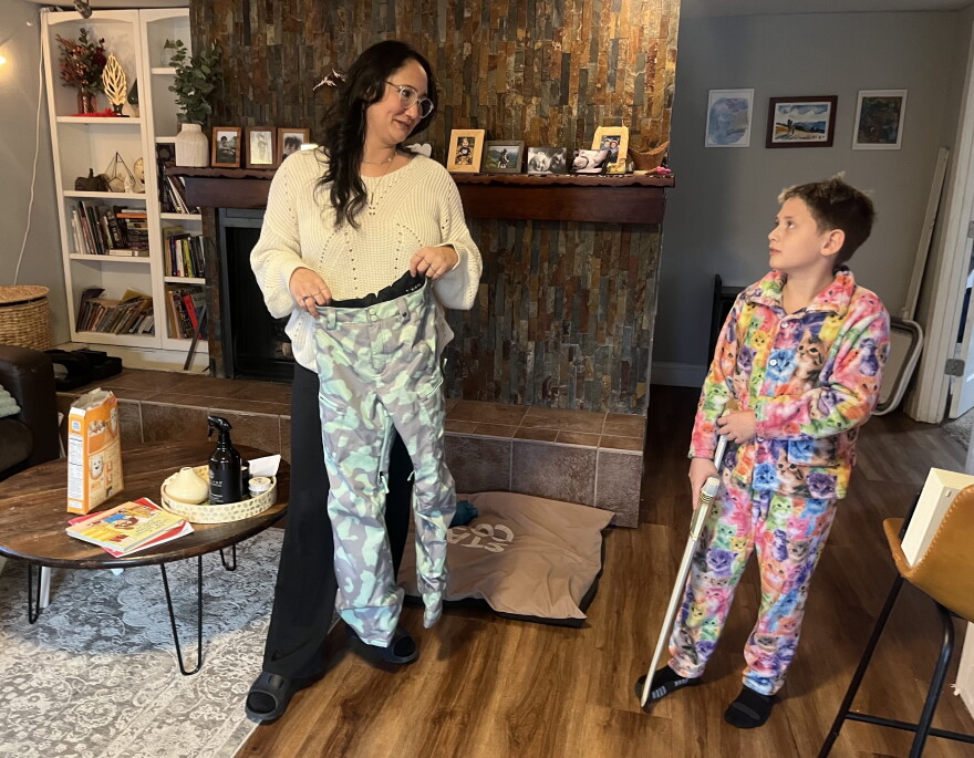 Naomi Estes holds up the like-new name-brand snow pants she recently found for her son Wesley (right) at Goodwill. They were exactly what she was looking for, she said.