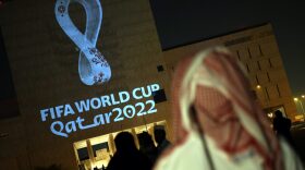 People gather at the capital Doha's traditional Souq Waqif market while the official logo of the FIFA World Cup Qatar 2022 is projected on the front of a building.