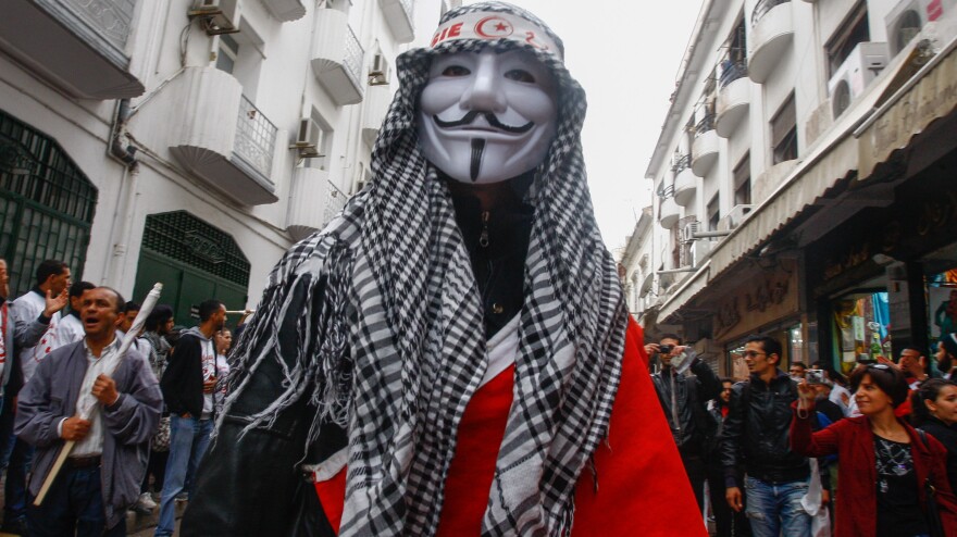 <strong><a href="http://menasolidaritynetwork.com/2012/05/02/tunisia-thousands-fill-streets-to-celebrate-may-day/">Tunis, Tunisia</a>:</strong> A man wears an Anonymous mask during a May Day rally on May 1.