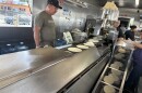 Tortillas being rolled out on a conveyor belt from a machine, alongside workers at Tortilleria Ortuño, on the afternoon of April 10, 2026.